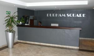 a man sitting at the counter of a dufrin square store at Durham Square Apartments in Cape Town