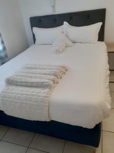 ein Bett mit einer weißen Decke und Kissen darauf in der Unterkunft Durham Square Apartments in Kapstadt