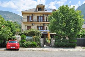 a red car parked in front of a house at Hotel Aoos in Konitsa