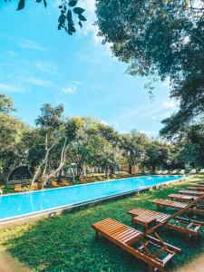a large swimming pool with wooden picnic tables next to it at NIVADOO RESORT SIGIRIYA in Sigiriya