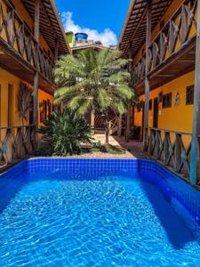 a swimming pool in front of a building with a palm tree at Pousada Pérola Do Morro in Morro de São Paulo