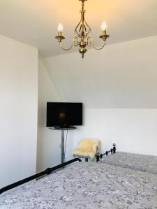 a bedroom with a bed with a television and a chandelier at Skye View-Skye Bridge House in Kyle of Lochalsh