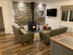 a living room with a stone wall and a fireplace at Bee Cottage in East Lydford