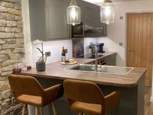 a kitchen with a sink and a counter with chairs at Bee Cottage in East Lydford