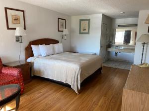 a hotel room with a bed and a red chair at Howard Johnson by Wyndham Azusa in Azusa