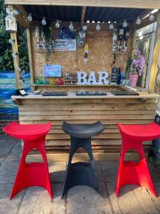 zwei rote und schwarze Hocker vor einer Bar in der Unterkunft Your urban retreat -Birmingham - Great for groups and reunions-With Undercover Hot Tub outside bar in Birmingham