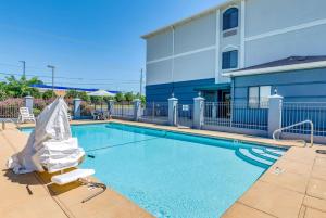a swimming pool with a chair next to a building at Days Inn & Suites by Wyndham Prattville-Montgomery in Prattville