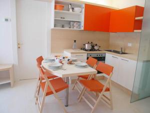 uma cozinha com uma mesa e cadeiras brancas e armários laranja em Residence Mirage em Grado