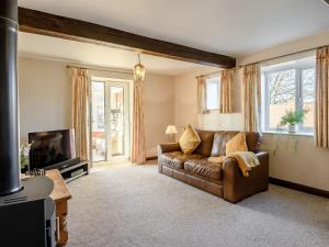 a living room with a leather couch and a television at Nightingale Lodge in Ropsley