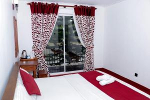 Un dormitorio con una cama con cortinas rojas y blancas y una ventana en Sadhara River View Lodge en Kandy