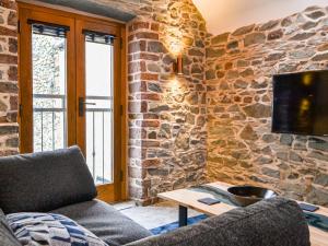 a living room with a stone wall with a couch and a tv at The Old Stable in Keswick