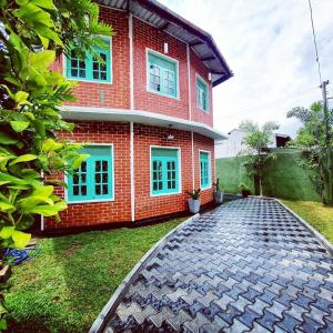Casa de ladrillo rojo con ventanas azules y entrada en Sadhara River View Lodge en Kandy