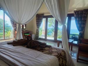 a woman laying on a bed in a bedroom with windows at Bali Bhuana Villas in Amed