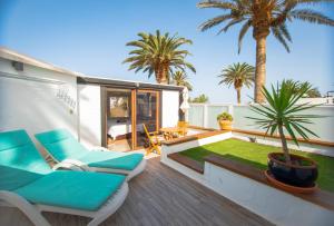 a patio with chairs and palm trees on a deck at The Luxury Penthouse at Casita Palmera in Haría