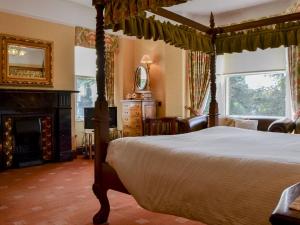 1 dormitorio con cama con dosel y chimenea en Newstead, en Windermere