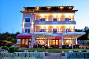 ein Gebäude mit Tischen und Sonnenschirmen davor in der Unterkunft Anastassiou Hotel in Kastoria