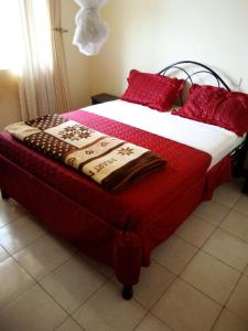 Una cama con almohadas rojas y una manta. en Westcliff Hotel en Lira