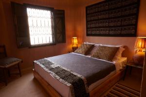 1 dormitorio con 1 cama con 2 lámparas y una ventana en Kasbah Flilou, en Aït Ougliff