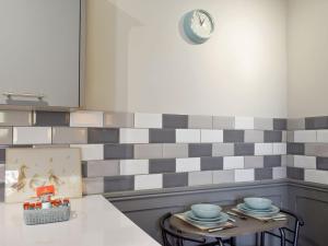 a kitchen with a table and a clock on the wall at Slant End Cottage in Golcar