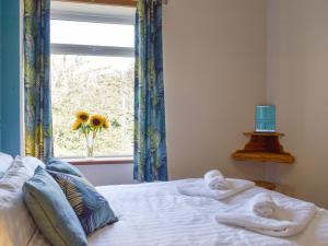 a bedroom with towels on a bed with a window at Slant End Cottage in Golcar