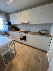 a kitchen with white cabinets and a wooden floor at Linden Monteur Apartment in Rodenbach