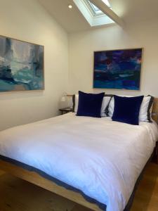 a bedroom with a large white bed with blue pillows at The Little Studio in Penzance