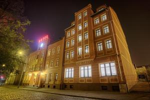 a building with a sign on top of it at night at Hotel Kamieniczka in Legnica