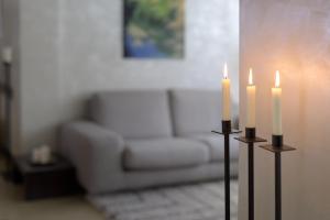 Methis Hotel & SPA في بادوفا: شمعتين في غرفة المعيشة مع أريكة