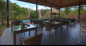 a restaurant with tables and chairs and a pool at Bintang Bungalow in Nusa Penida