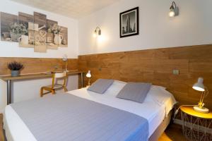 een slaapkamer met een wit bed en een houten muur bij Hôtel du Midi in Domène