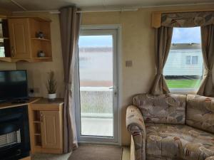 a living room with a couch and a sliding glass door at 8 berth central heated on Coral Beach ABI CB in Ingoldmells