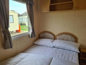 a bed in a small room with a window at 8 berth central heated on Coral Beach ABI CB in Ingoldmells