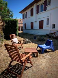 2 sillas de madera y una silla azul en un patio en Le Studio Rouge de la Gare, en Vieux-Boucau-les-Bains