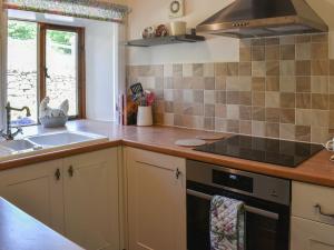 a kitchen with a sink and a stove at Lodge Farm Cottage in Haworth