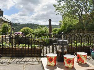 uma mesa com duas canecas numa mesa em frente a uma vedação em Lodge Farm Cottage em Haworth