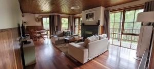 a living room with white couches and a table at Tall Trees Eco Retreat in Apollo Bay