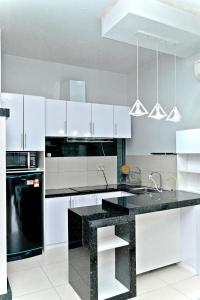 a kitchen with white cabinets and a black counter top at Bulan Guesthouse Imago in Kota Kinabalu