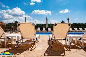 a pair of lounge chairs on a patio next to a swimming pool at Monix Palace Zlatibor in Zlatibor