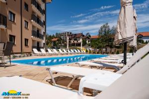 a row of lounge chairs and a swimming pool at a hotel at Monix Palace Zlatibor in Zlatibor