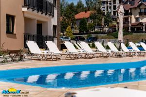 a row of lounge chairs next to a swimming pool at Monix Palace Zlatibor in Zlatibor