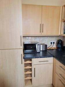 a kitchen with a microwave on top of a counter at Superb Loch Side Apartment with Sea & Sunset Views in Helensburgh