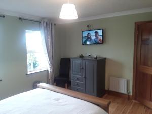 a bedroom with a bed and a tv on the wall at Doonard Manor B&B in Craughwell