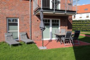 a patio with a table and chairs and an umbrella at Seepferdchen in Greetsiel