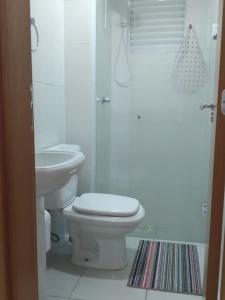 a white bathroom with a toilet and a sink at Apartamento ao lado da Vila Germânica in Blumenau