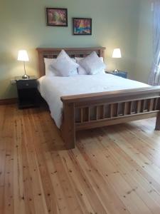 1 dormitorio con 1 cama grande de madera y 2 lámparas en Doonard Manor B&B, en Craughwell