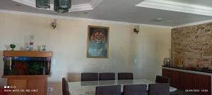 a dining room with a table and a painting on the wall at Hostel dos Pinheirais in Caieiras