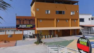 um edifício amarelo com um sinal em frente em Arraial do Cabo – Subuai Village - Aluguel Econômico em Arraial do Cabo