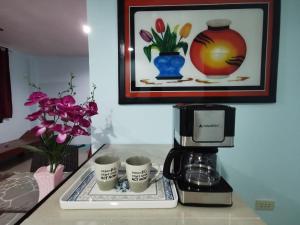 una cafetera y tres tazas de café en una barra en EZ & V Guesthouse, en Pagsanjan