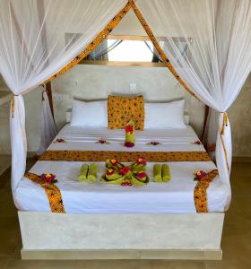 Una cama con sábanas blancas y flores. en Blue Reef Sport & Fishing Lodge and Bungalows, en Jambiani
