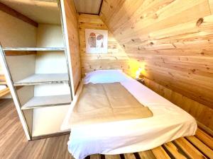 a small room with a bed in a wooden cabin at La cabane au pied des pistes in Chastreix